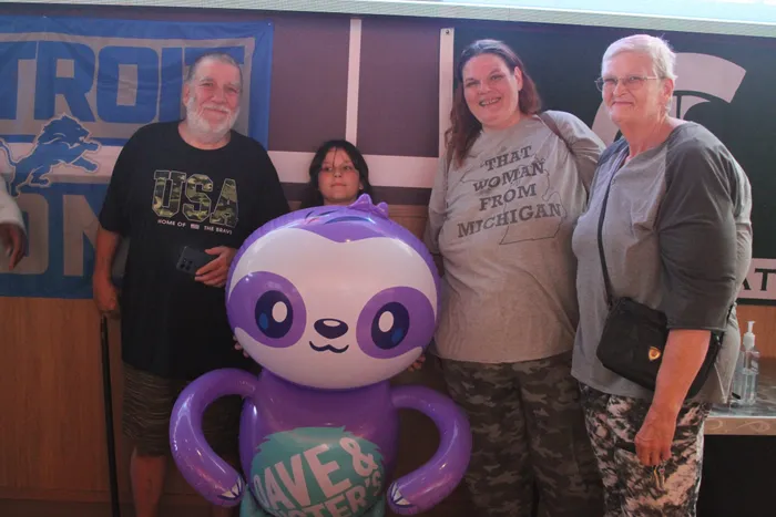 A family posing with an inflatable Dave & Buster's sloth mascot